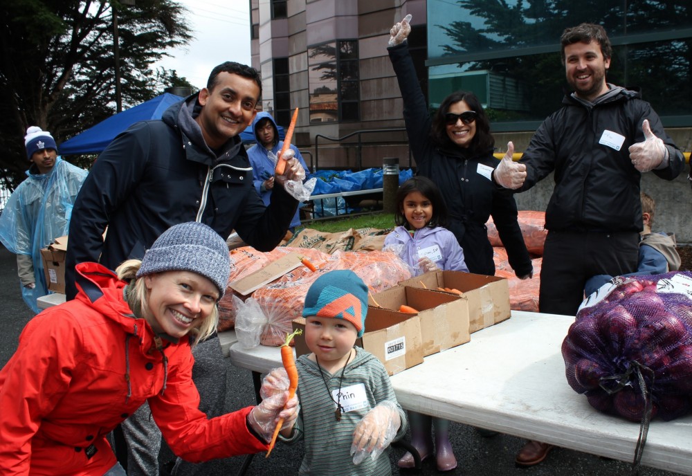 Preschool and Elementary School families distribute carrots on a rainy morning at the Excelsior C...